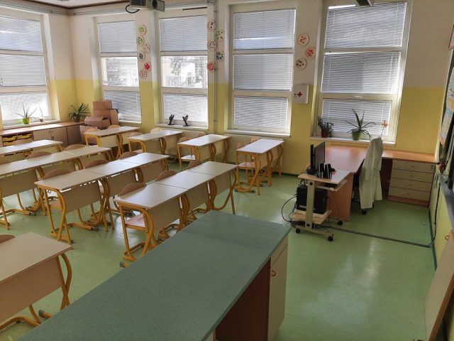 Svetla šolska učilnica z lesenim in barvnim pohištvom